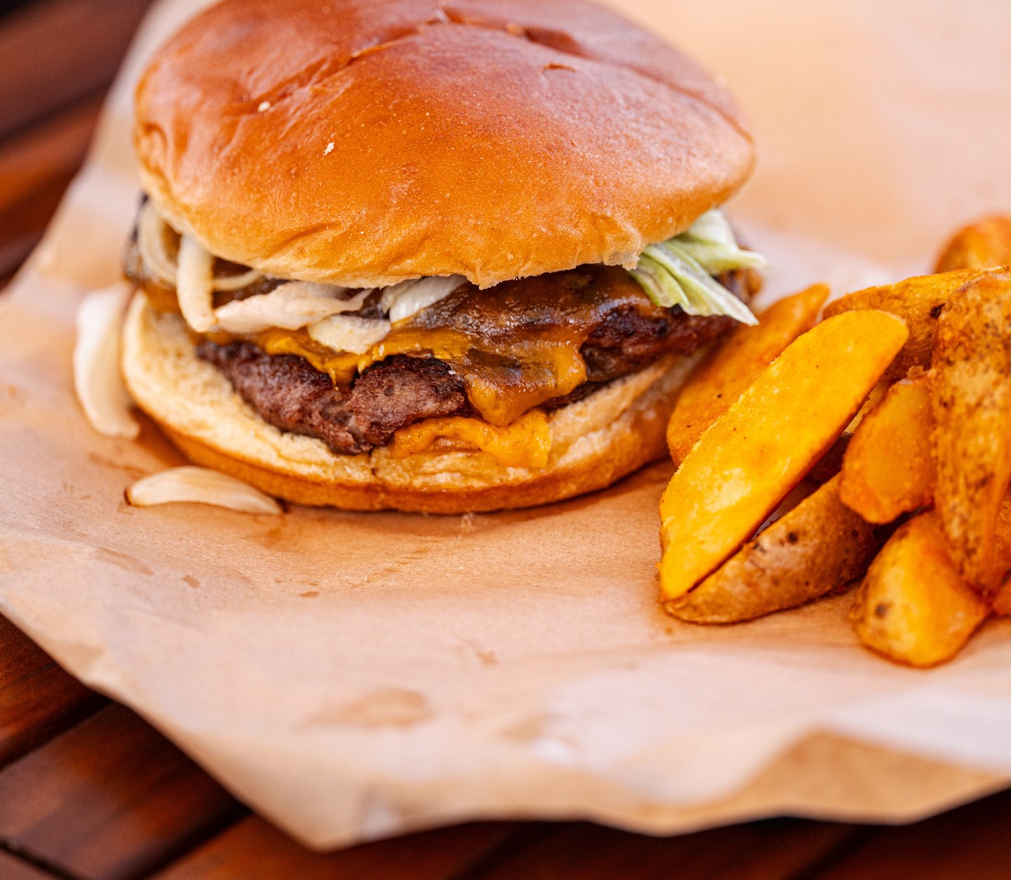 AIRA Burger con queso fundido y patatas gajo, servida en la terraza